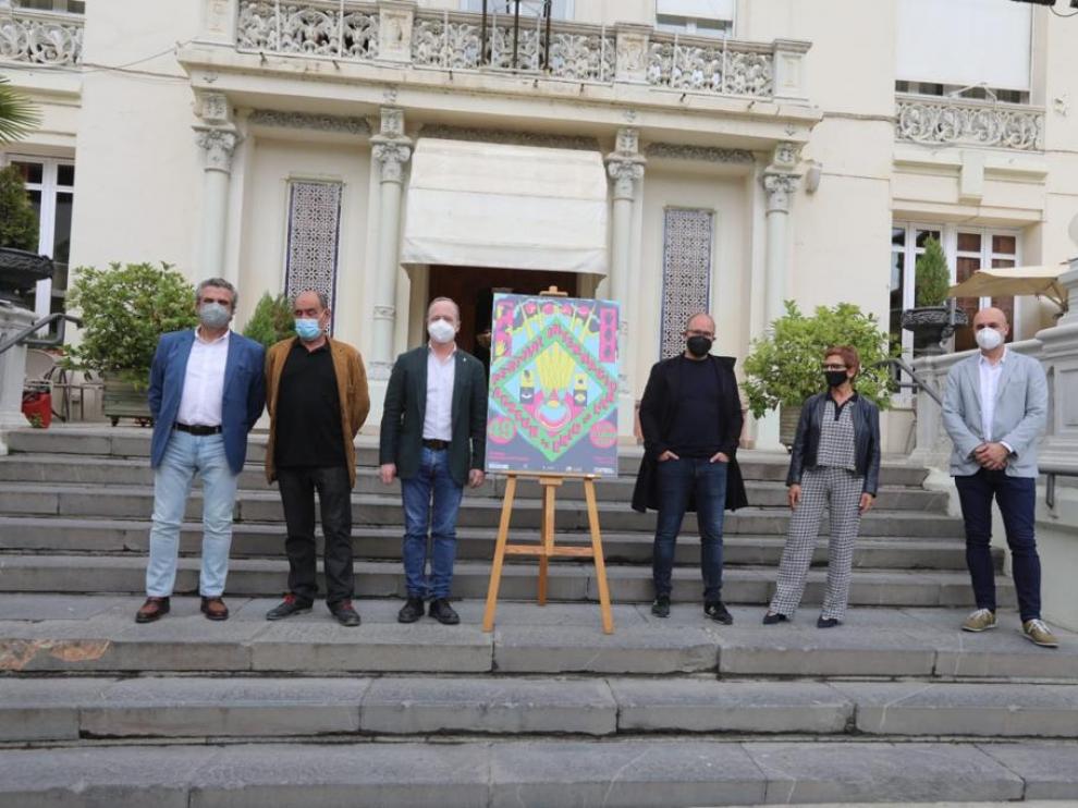 representantes de las entidades que organizan y patrocinan el festival de cine de huesca en la escalera del casino junto al cartel